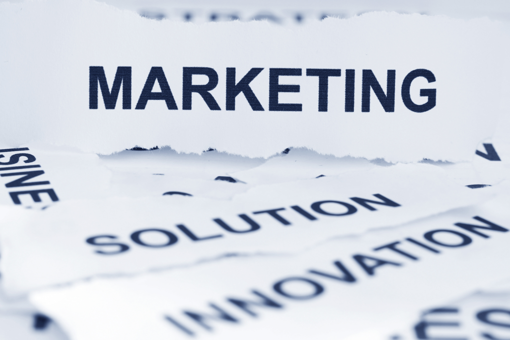 Torn white paper strips displaying the printed words "MARKETING," "SOLUTION," and "INNOVATION" in blue text.