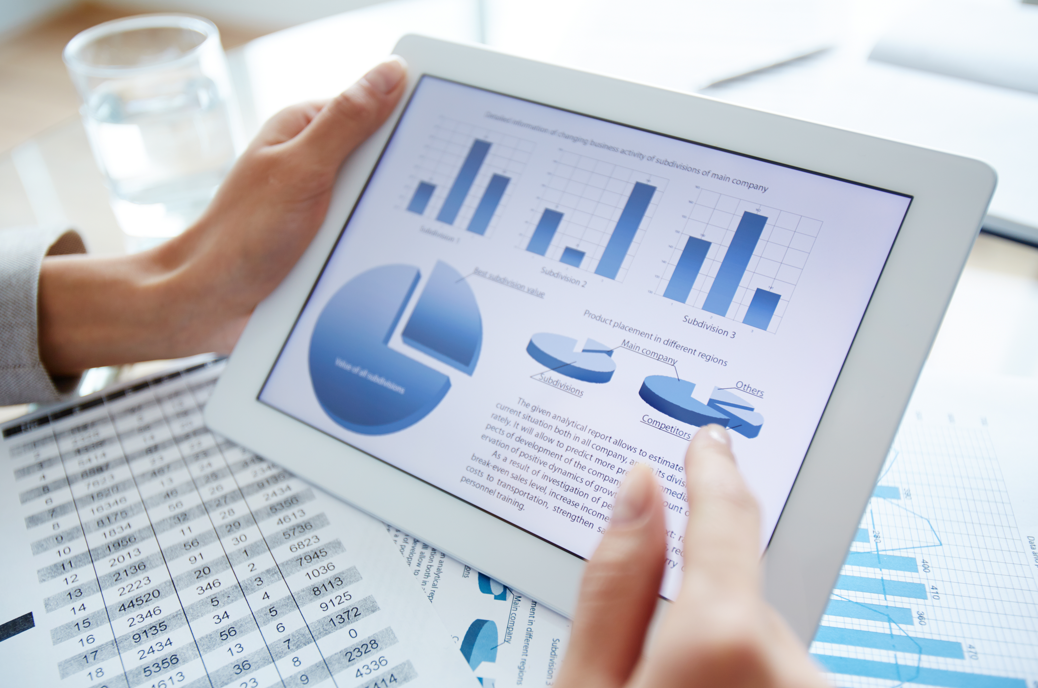 A person holding a tablet displaying financial charts and graphs.